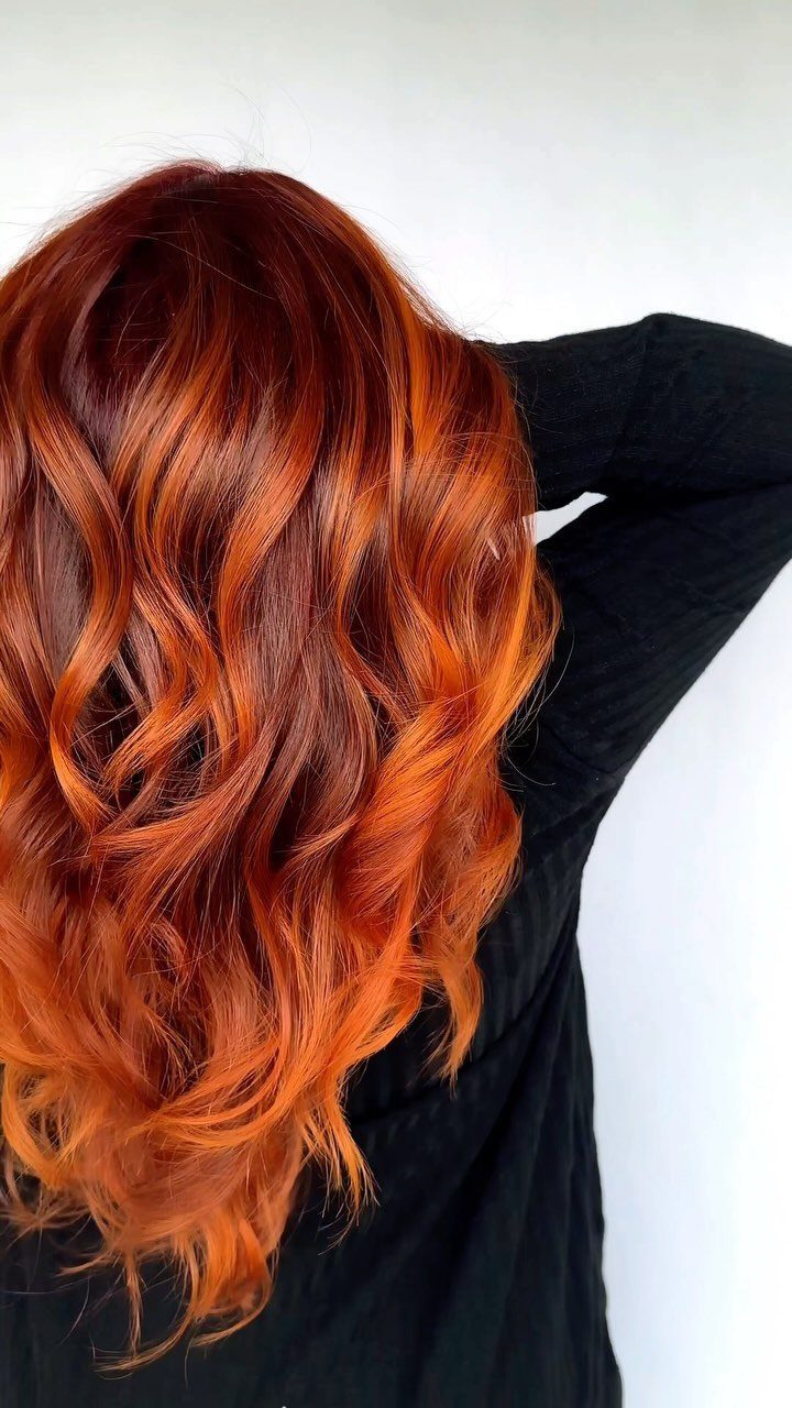 Wavy dark auburn hair with vivid copper-red balayage lengths