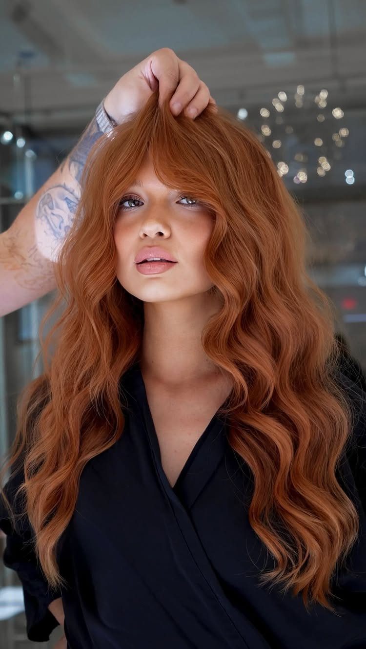 Woman with vivid copper-red layered waves and fringe in a salon