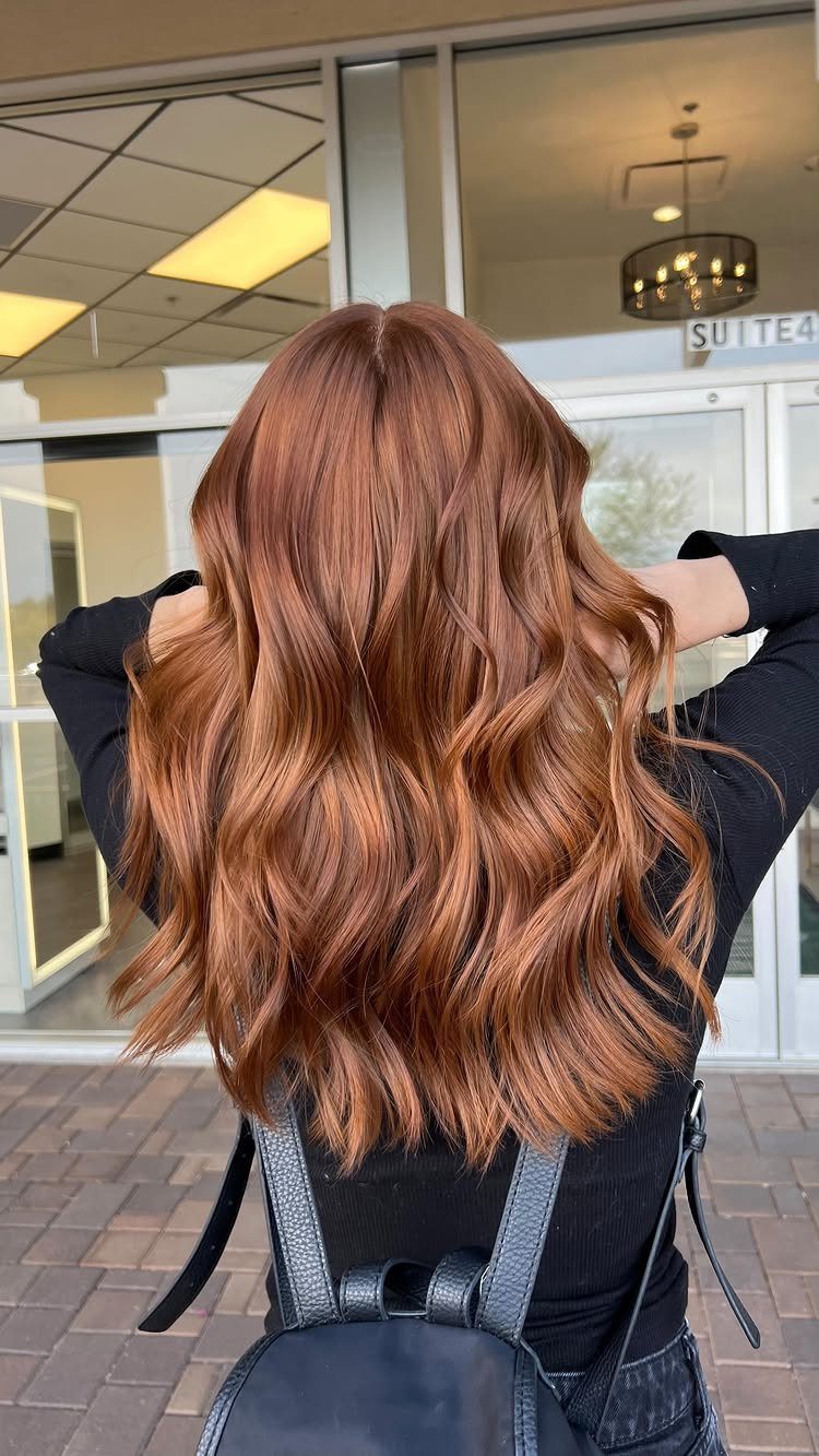 Long wavy ginger-copper hair with darker roots and dimensional color