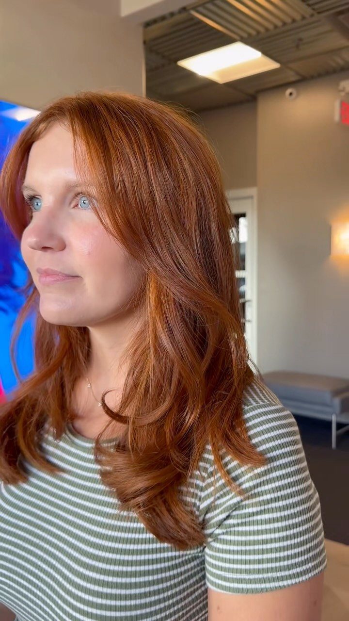 Woman with long, wavy rusty red hair and a center part