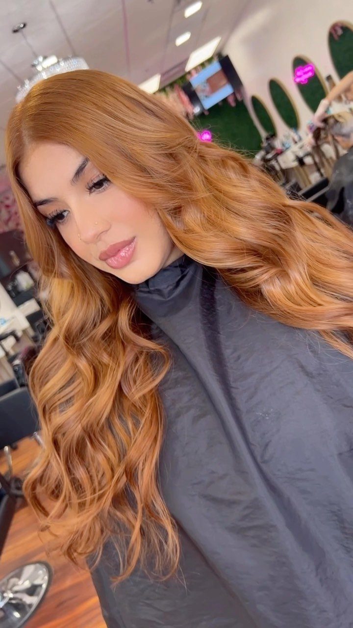 Woman showing long, wavy golden-ginger hair in a salon