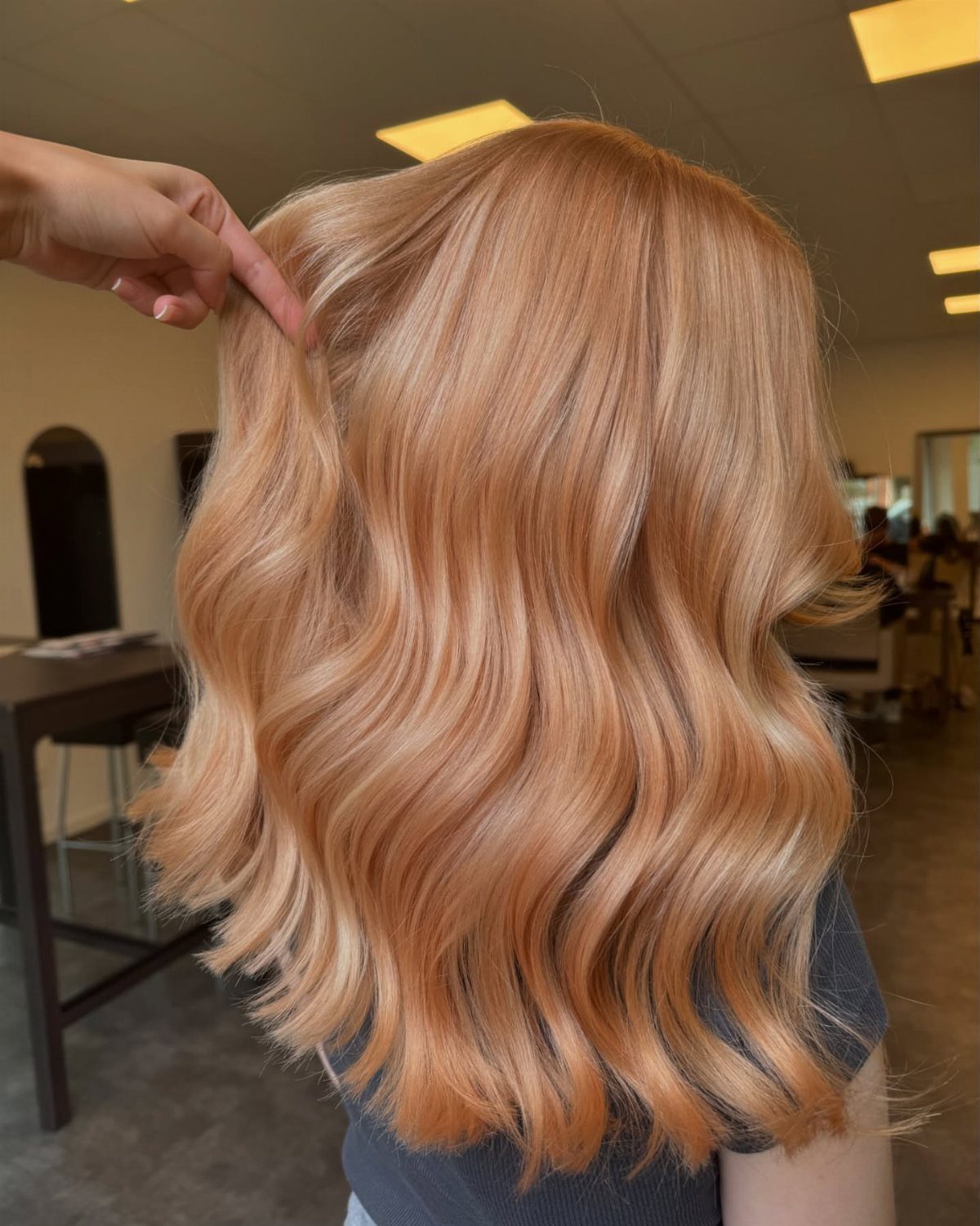 Wavy strawberry-blonde hair with soft peachy-red tones in a salon