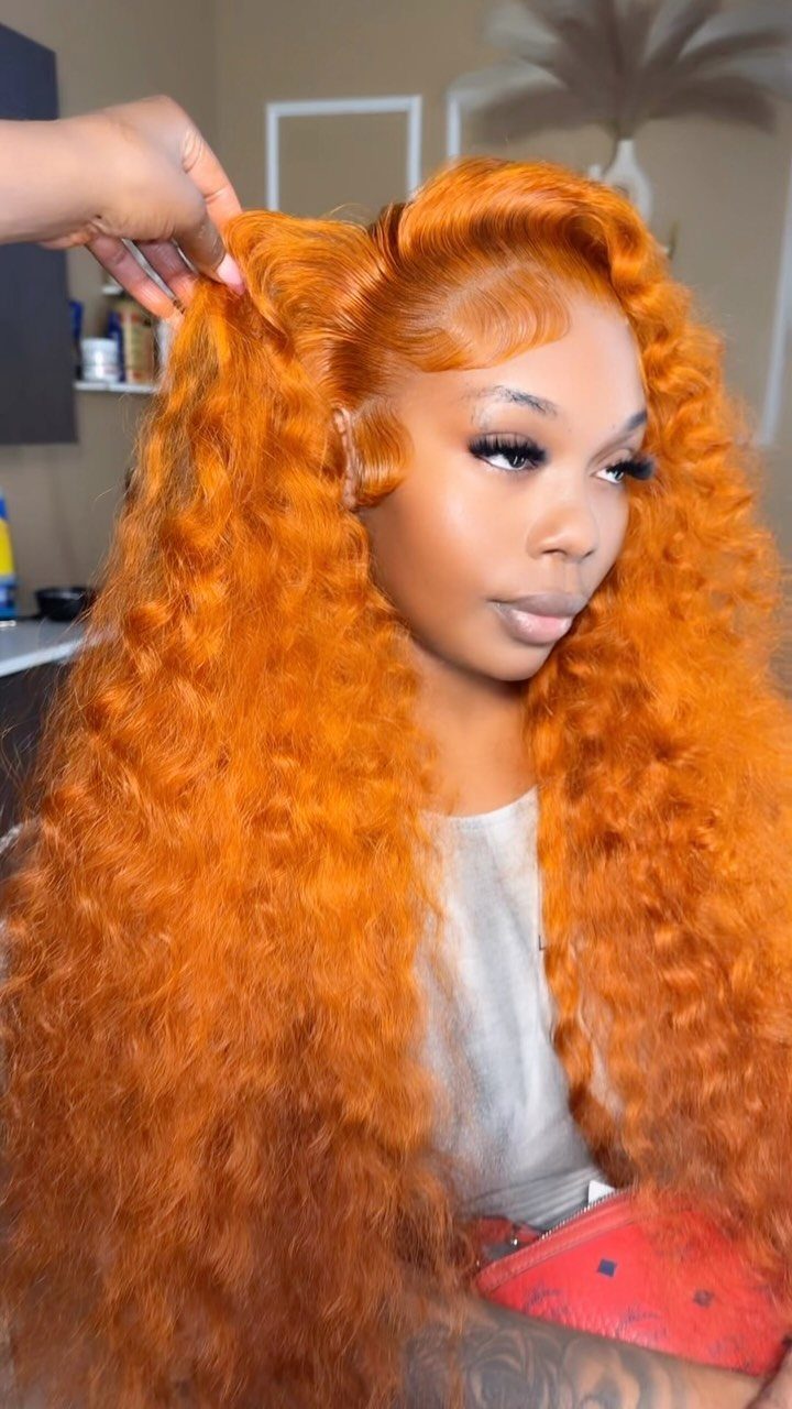 Woman with long, voluminous bright ginger curls seated in a salon