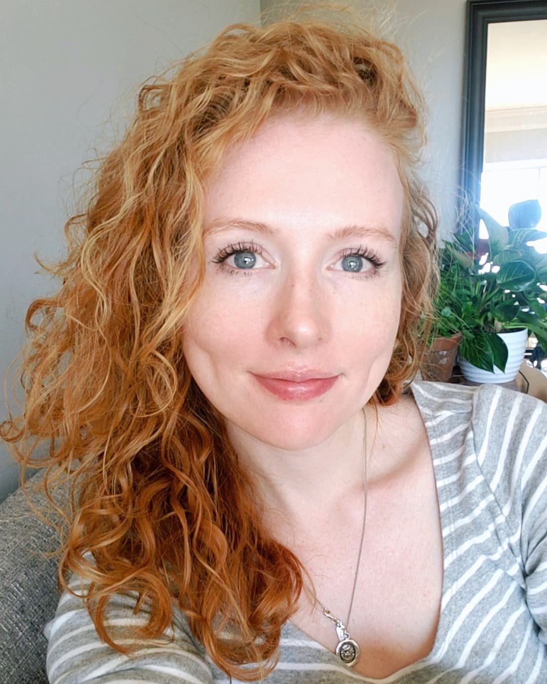Woman with long curly natural ginger-red hair seated indoors