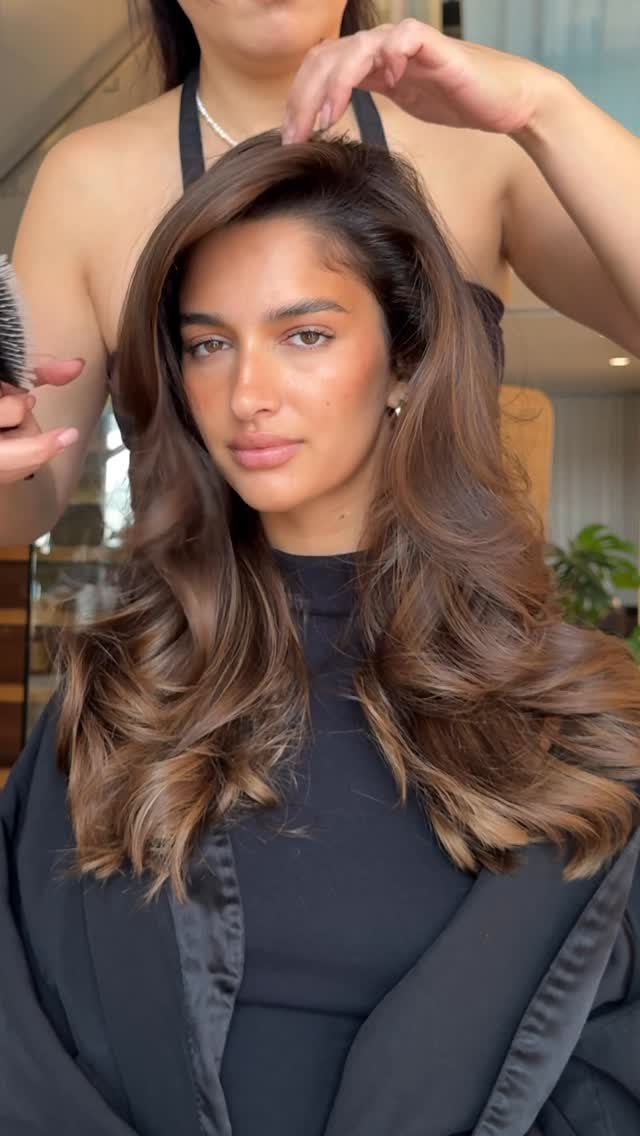 Woman with long brunette curls and subtle golden highlights in a salon