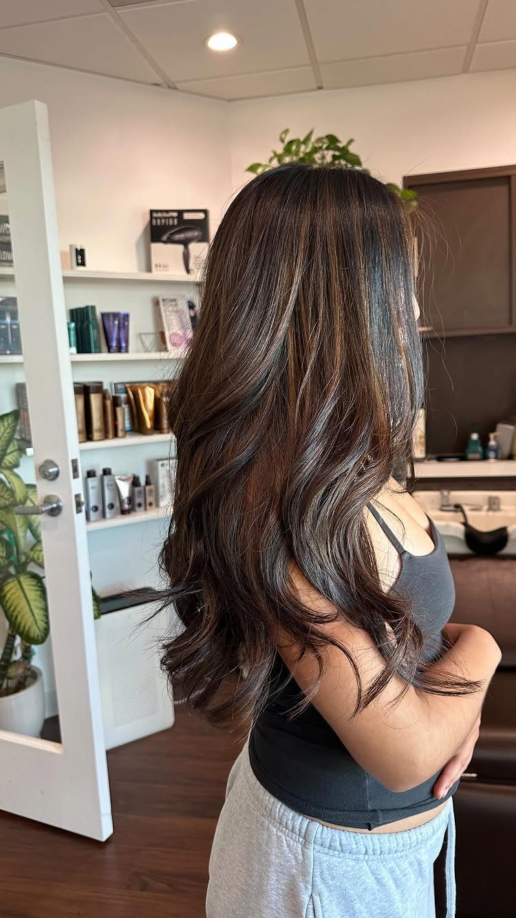 Long dark brunette hair with soft caramel balayage waves in a salon