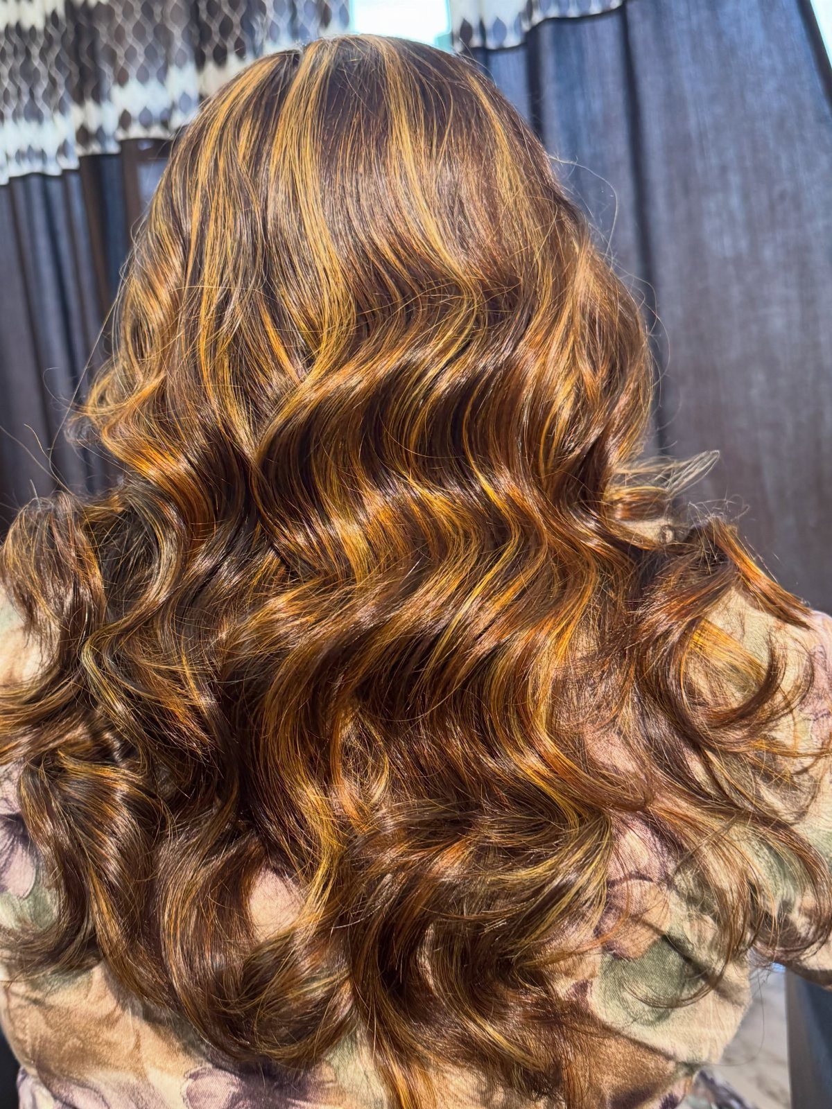 Long curled brown hair with golden highlights and warm reddish tones