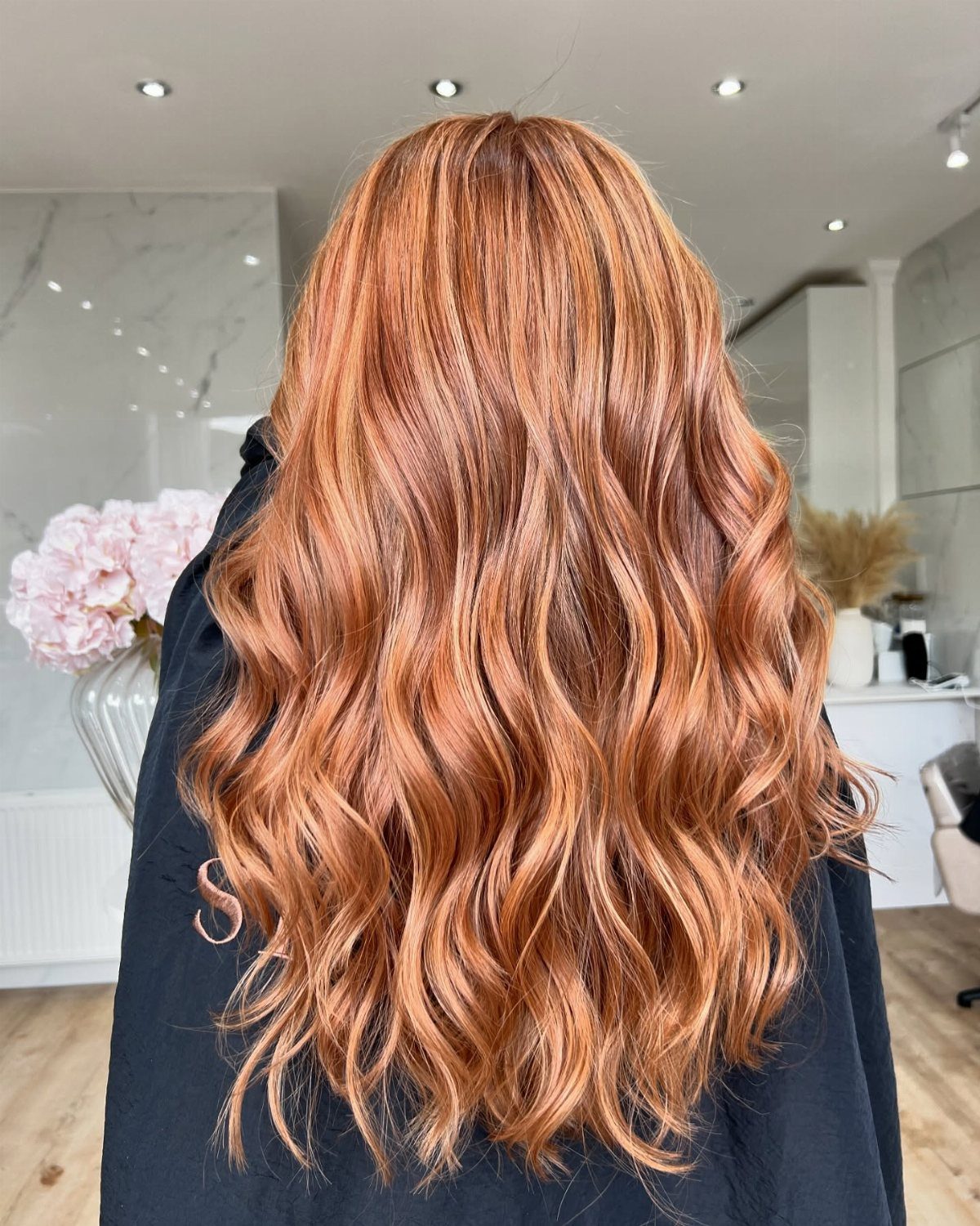 Long copper-brown waves with golden streaks displayed in a salon