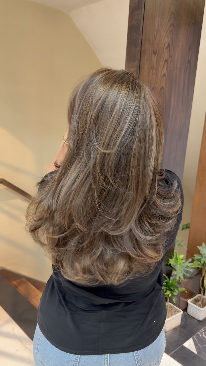 Long layered ash-brown hair with golden highlights and curled ends