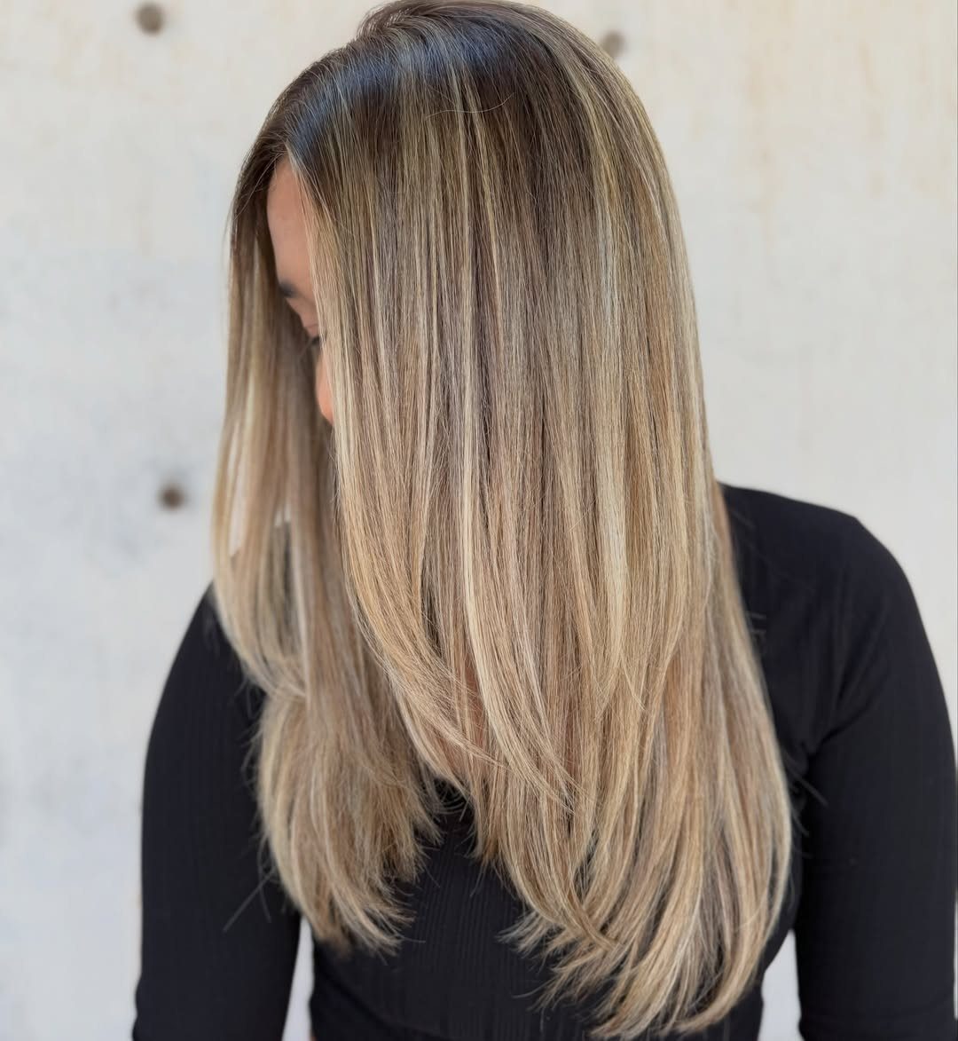 Long layered hair with dark brown roots and golden beige lengths