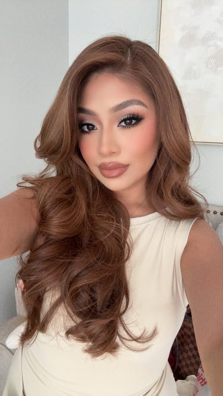 Woman with long, curled medium brown hair and warm golden highlights