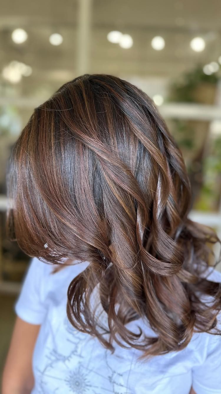 Long brunette curls show warm auburn hair with subtle caramel highlights