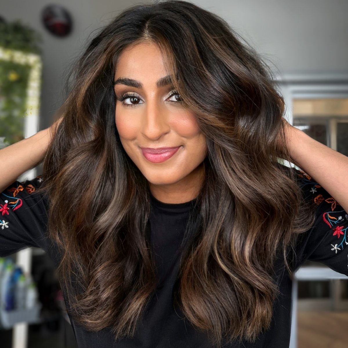 Woman displaying long dark hair with warm caramel balayage highlights