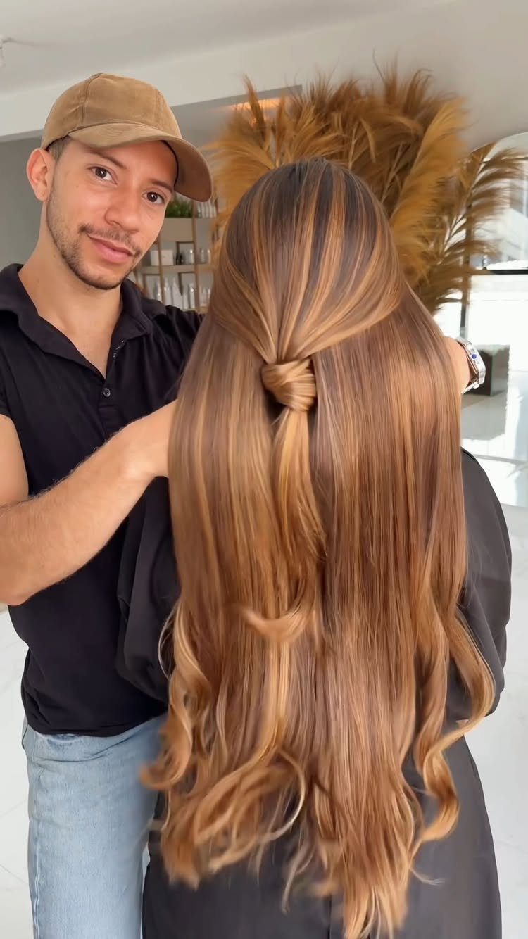 Long brown hair with caramel-blonde highlights styled in loose curls