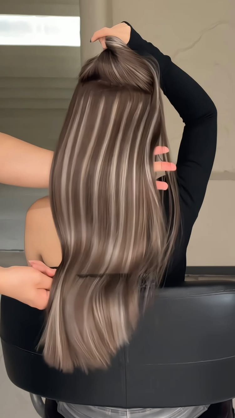 Long brown hair with broad caramel ribbon highlights displayed in a salon chair