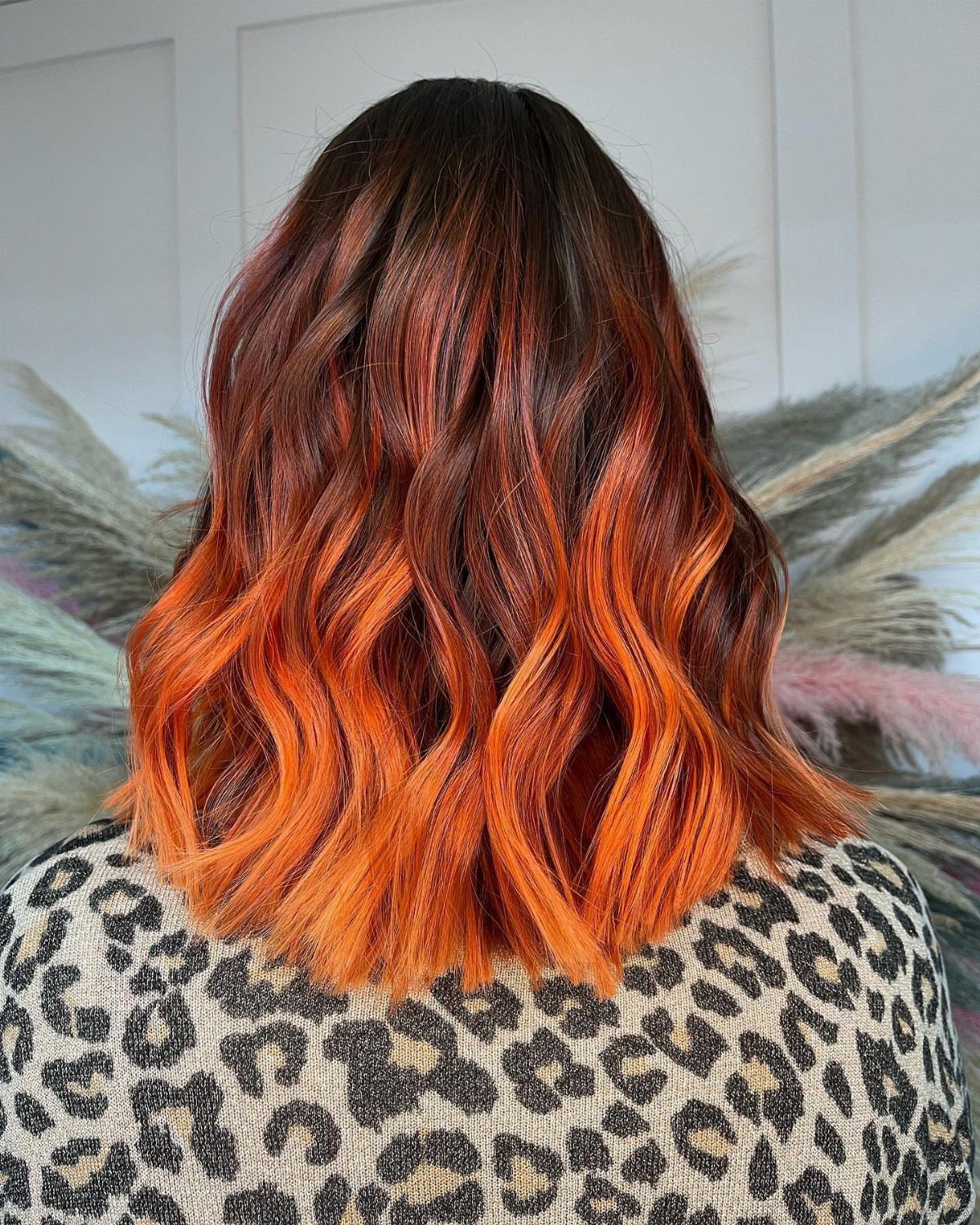 Wavy shoulder-length hair blending dark brown roots into vivid copper-orange ends