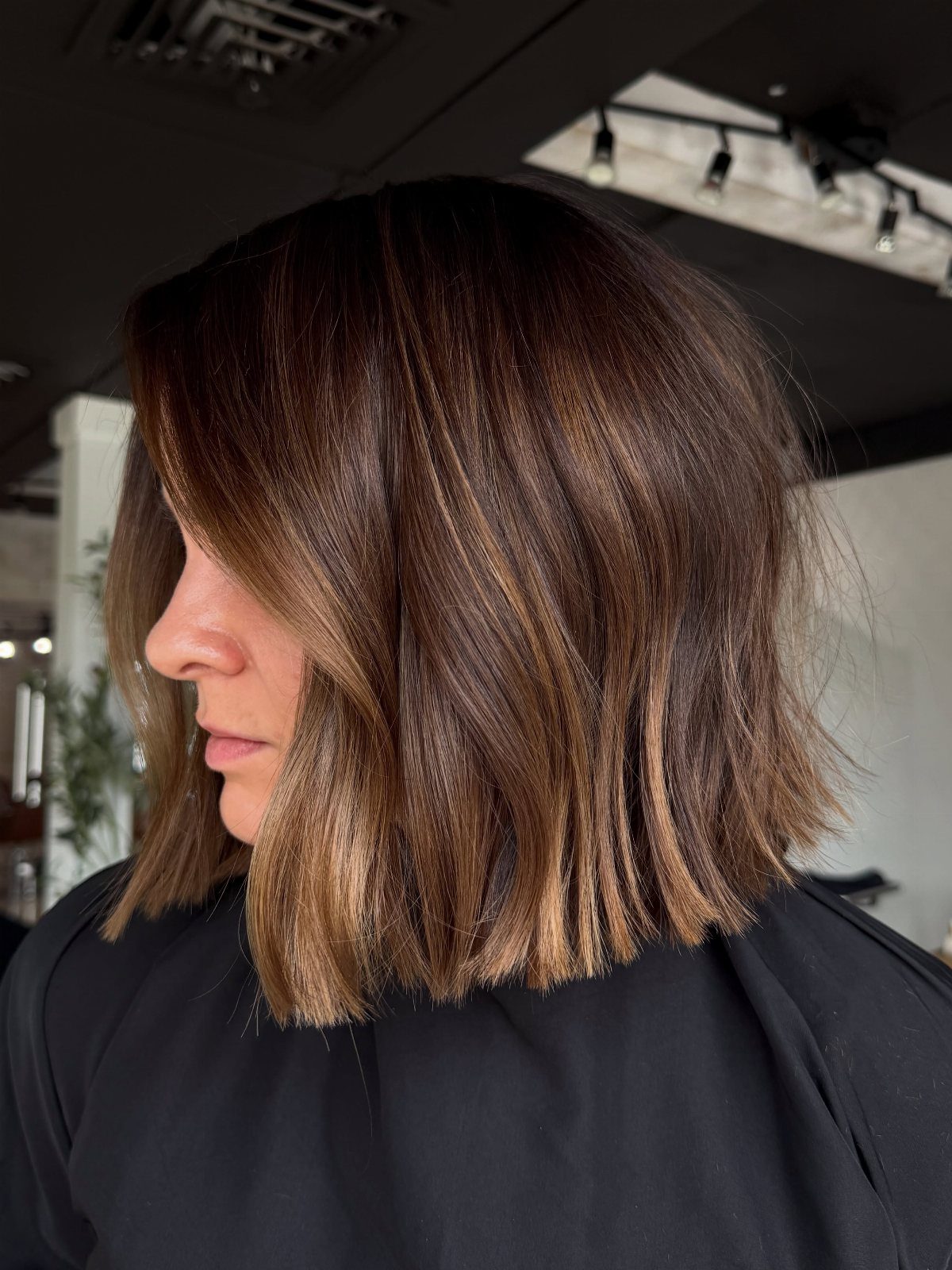 Shoulder-length brown bob with selected caramel blonde highlights in a salon