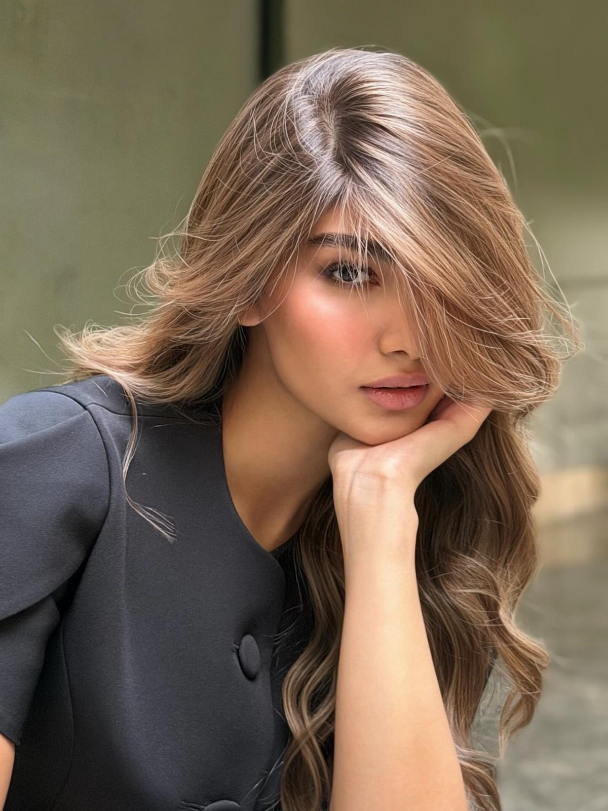Woman with long wavy tawny caramel highlighted hair in a dark blazer