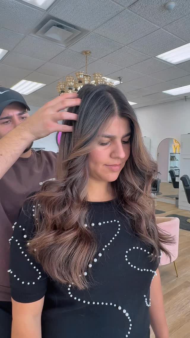 Woman with long wavy brown hair and subtle caramel strands in a salon