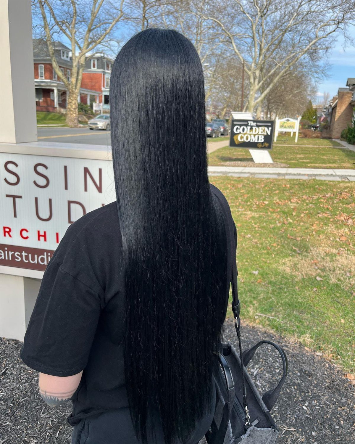 Long, straight black hair falls to an even edge down a black shirt.