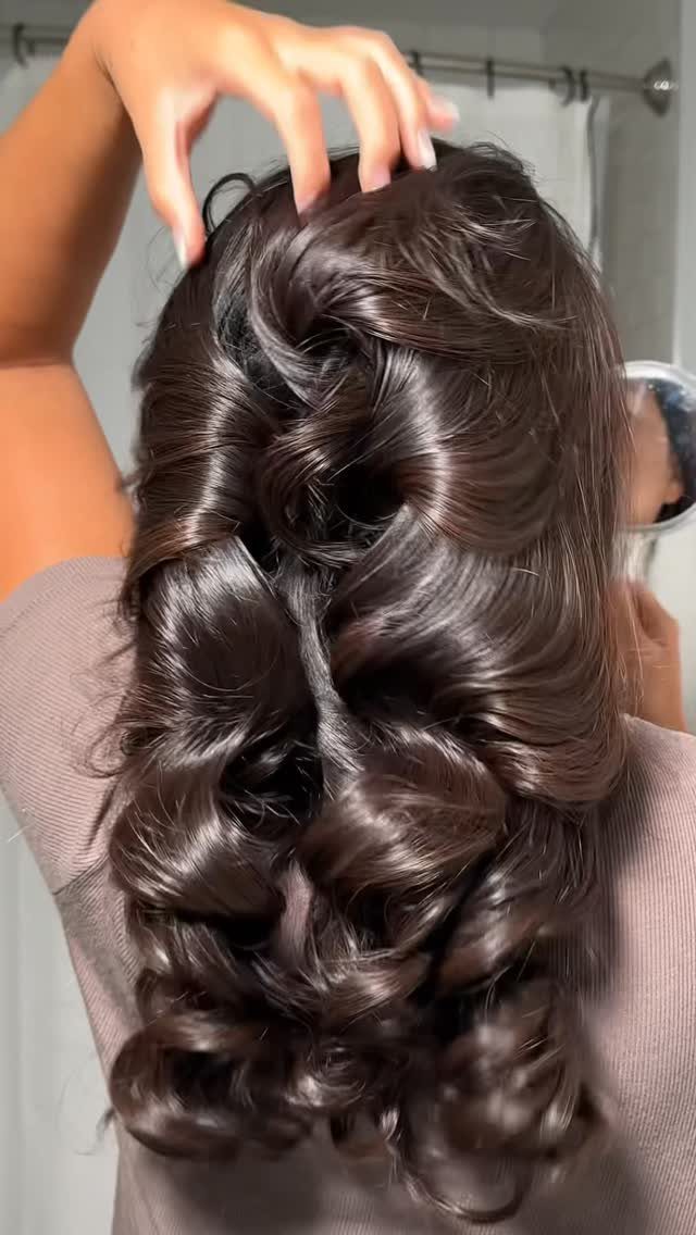 Long dark layered hair arranged in a voluminous curled updo with twists
