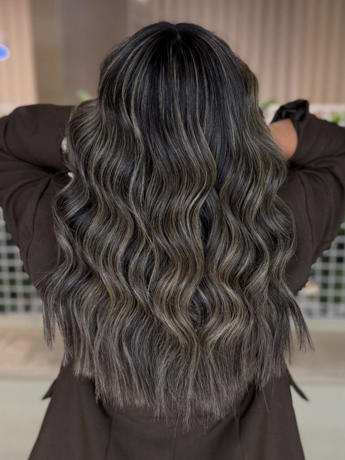 Long layered dark hair styled in loose waves with subtle lighter highlights