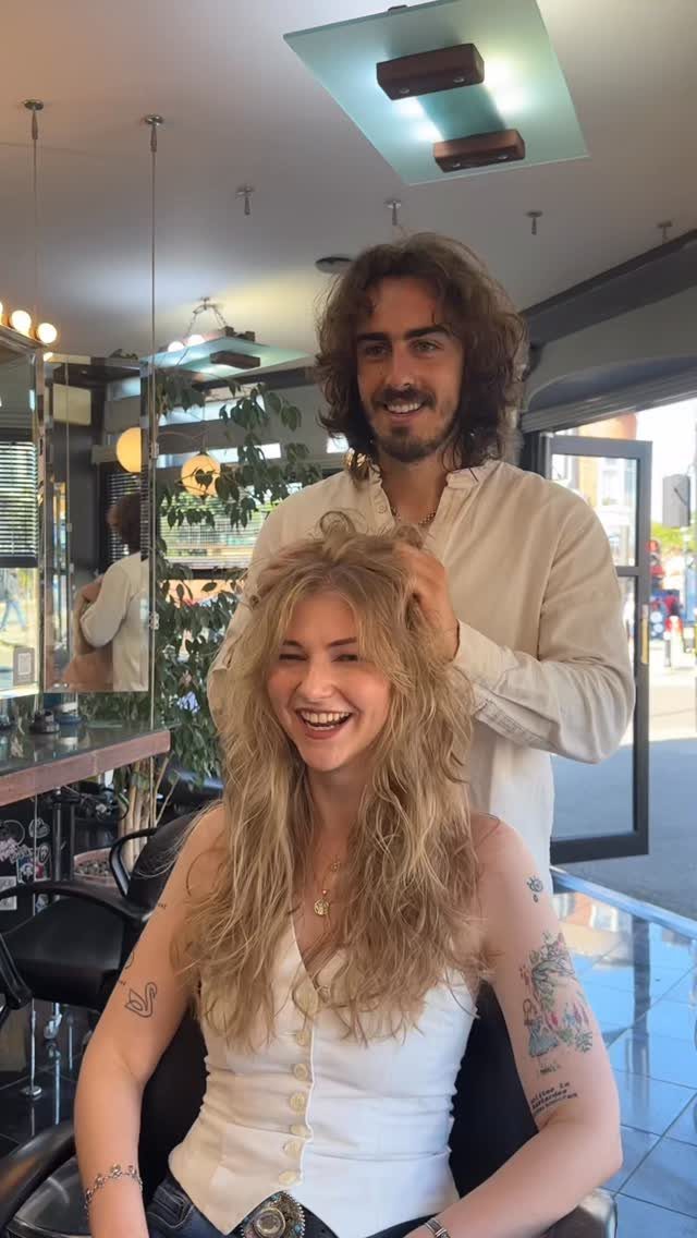 Woman with long, tousled blonde shaggy layers sitting in a salon chair