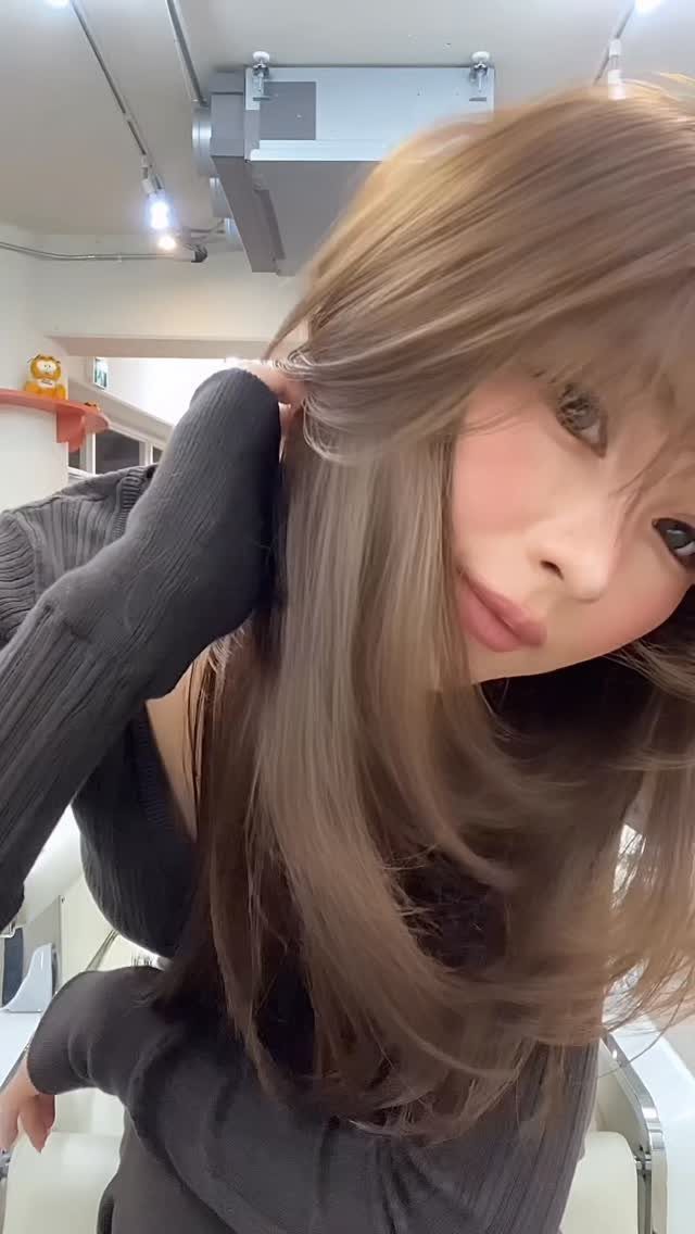 Woman displaying long, smooth layered hair with rounded ends in a salon