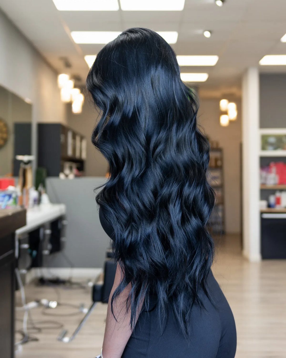 Long wavy blue-black hair catches cool highlights in a salon