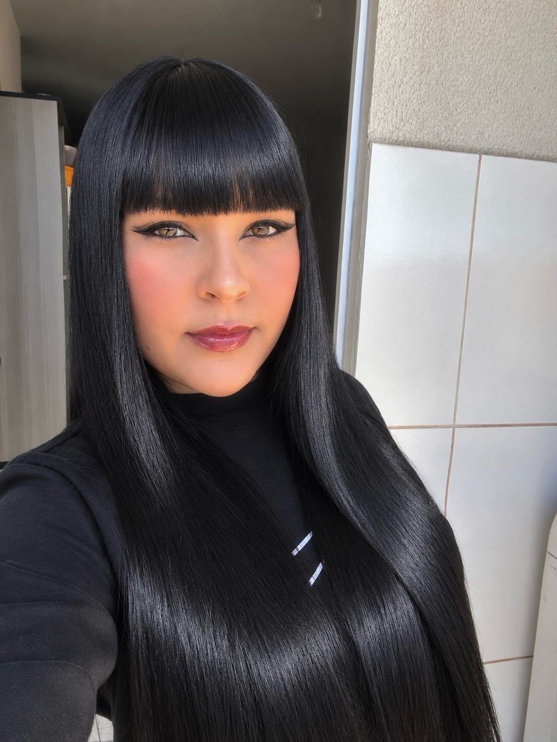 Woman with blunt bangs and long, glossy jet-black hair