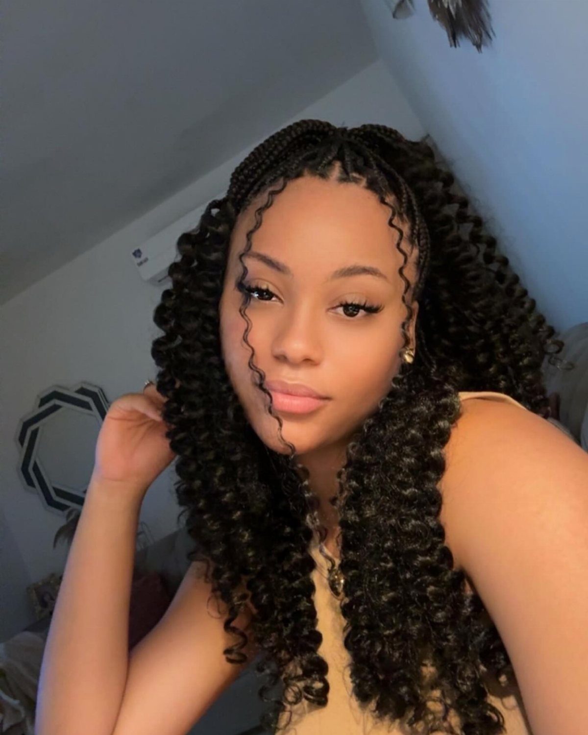 Woman with long black curls and small braids posing indoors