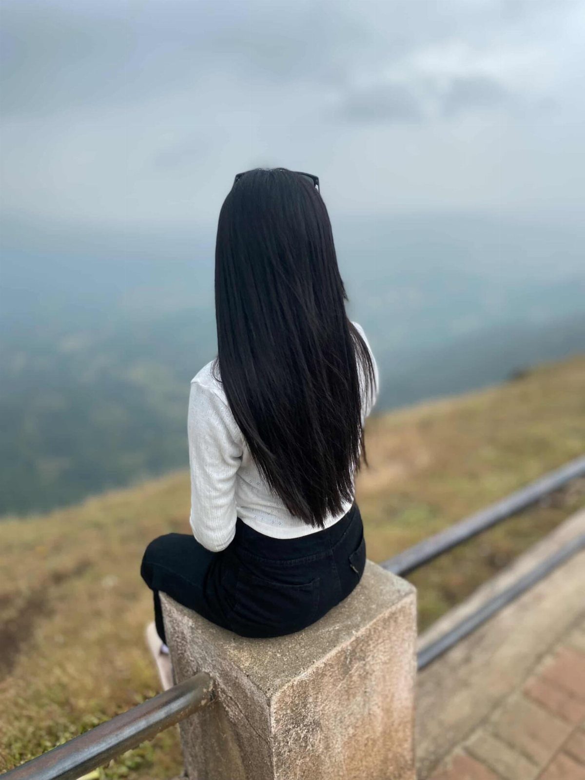 Long, straight black hair seen from behind against a cloudy landscape