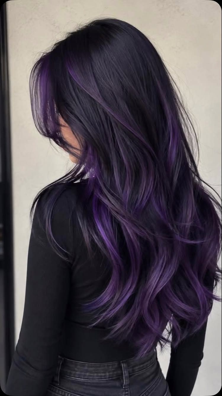 Long black hair with violet-purple streaks falls in loose waves