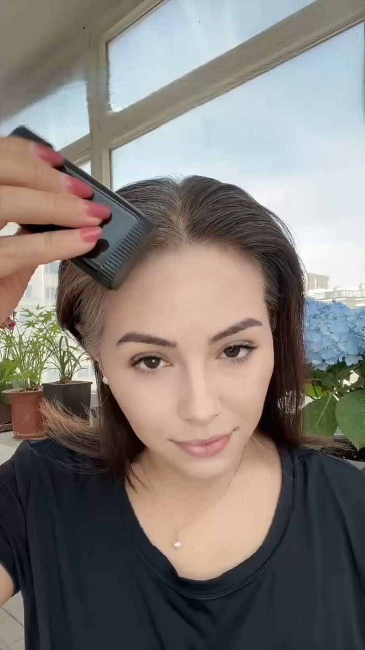 Woman parts dark hair at the roots with a black comb
