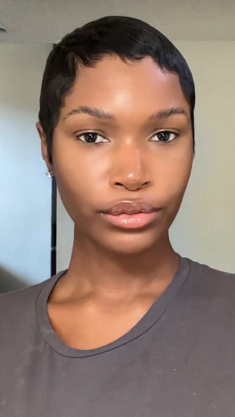 Short black hair frames a person's face in a close indoor portrait.