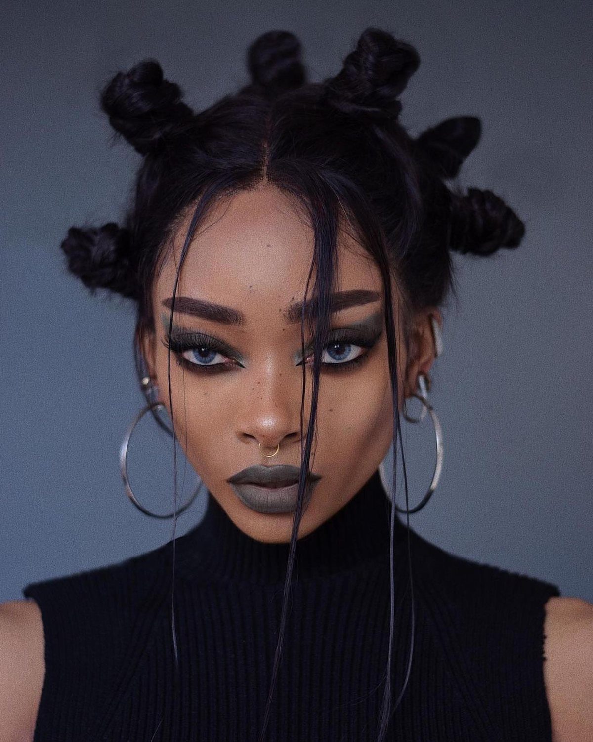 Woman with small coiled Bantu knots and loose strands framing her face