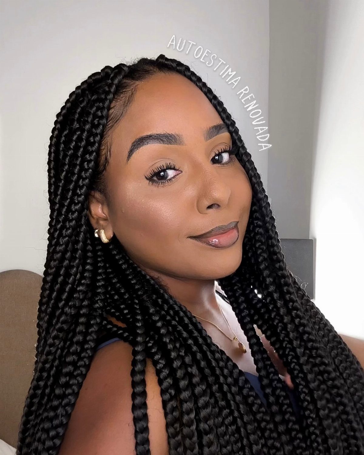 Woman with long, thick black box braids draped over her shoulders
