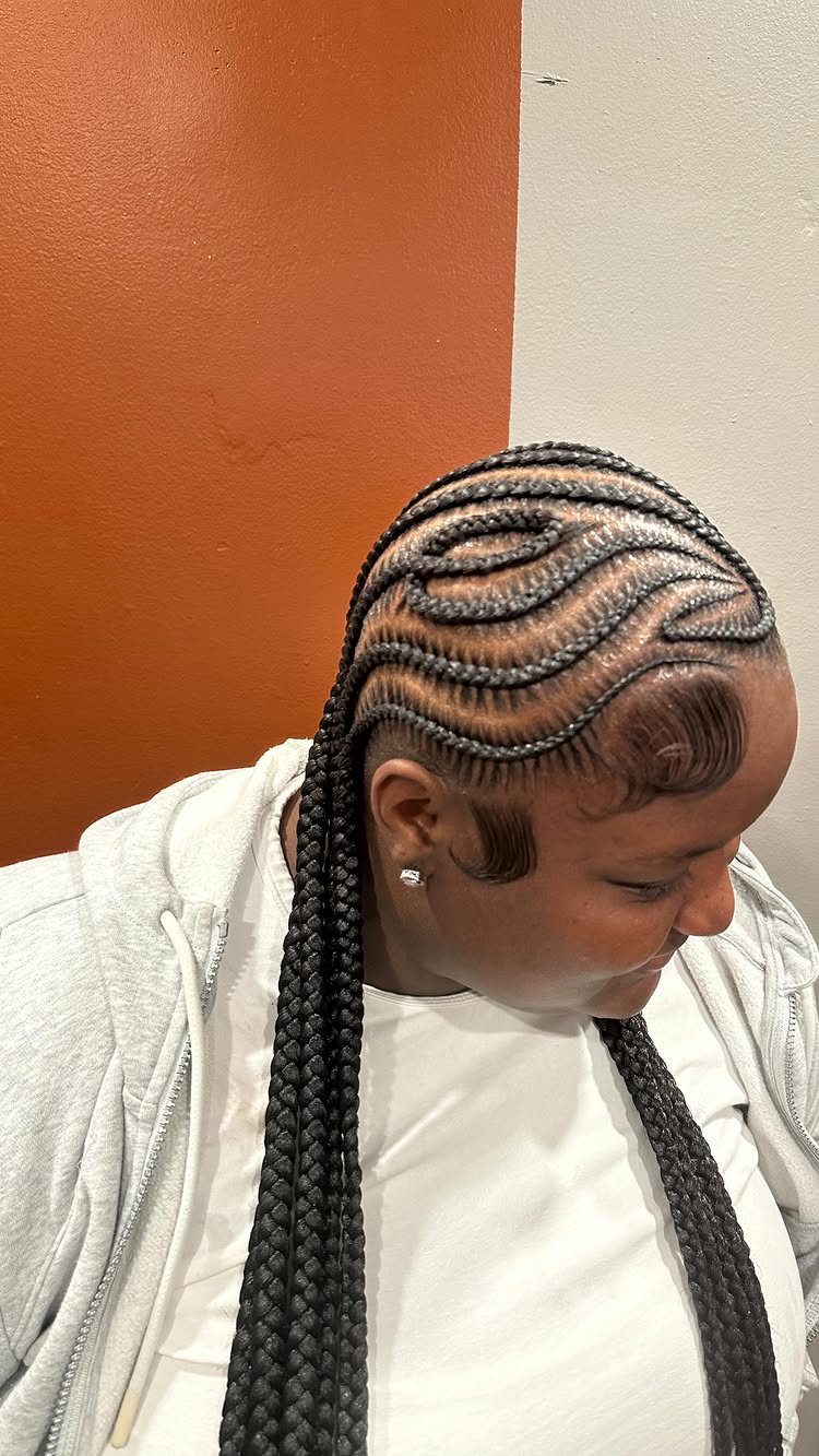 Black cornrows curve across the scalp and continue into long hanging braids