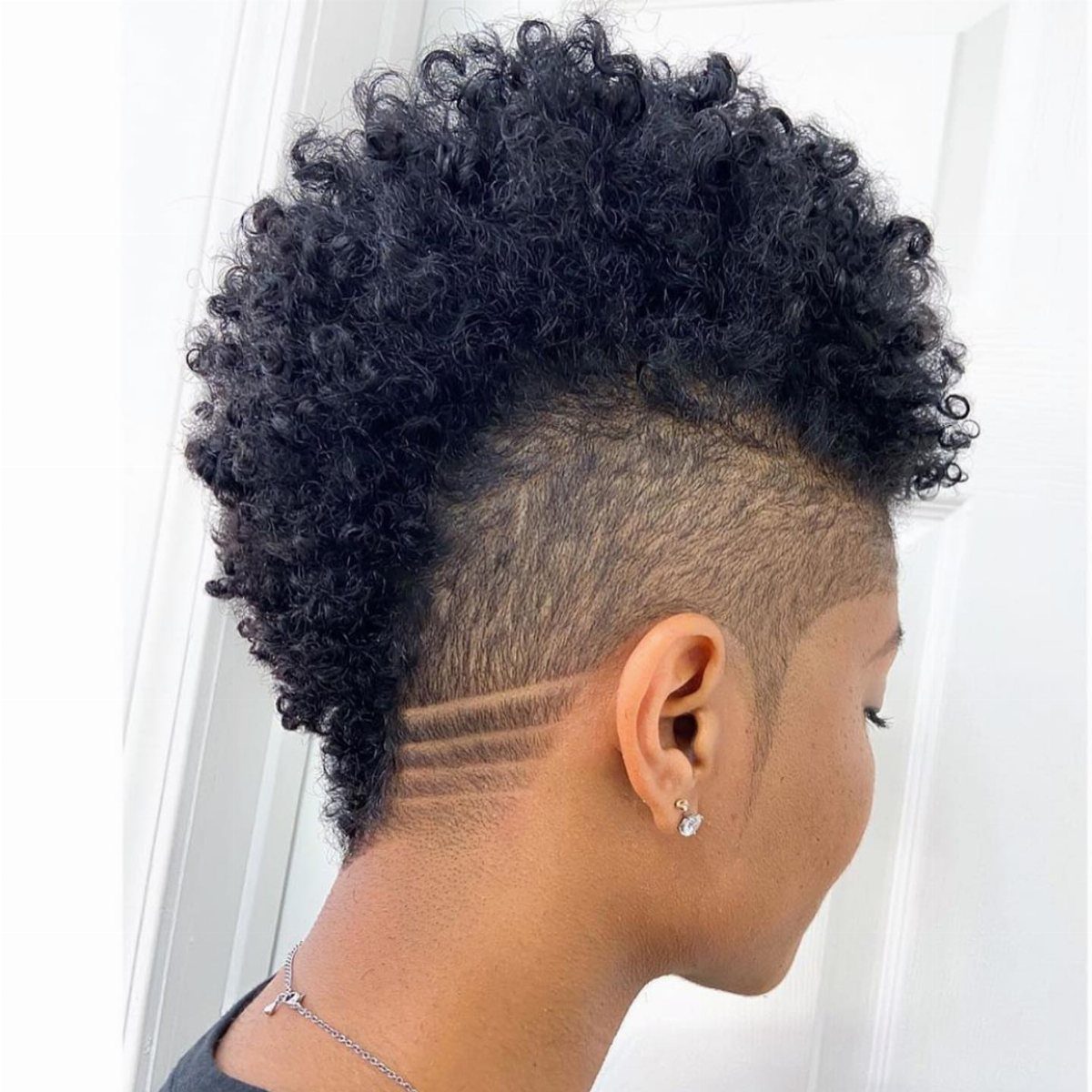Curly black fauxhawk with closely shaved sides and curved design lines