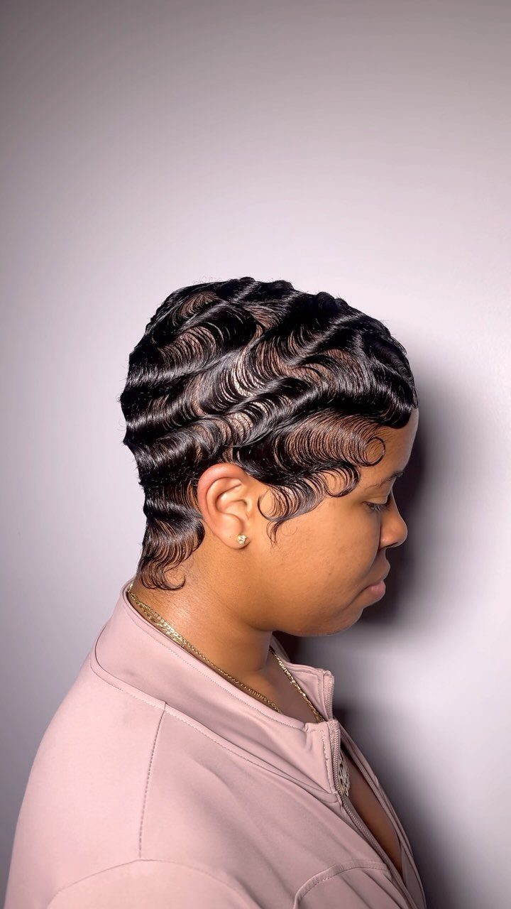 Side-profile hairstyle with glossy black hair sculpted into tight finger waves