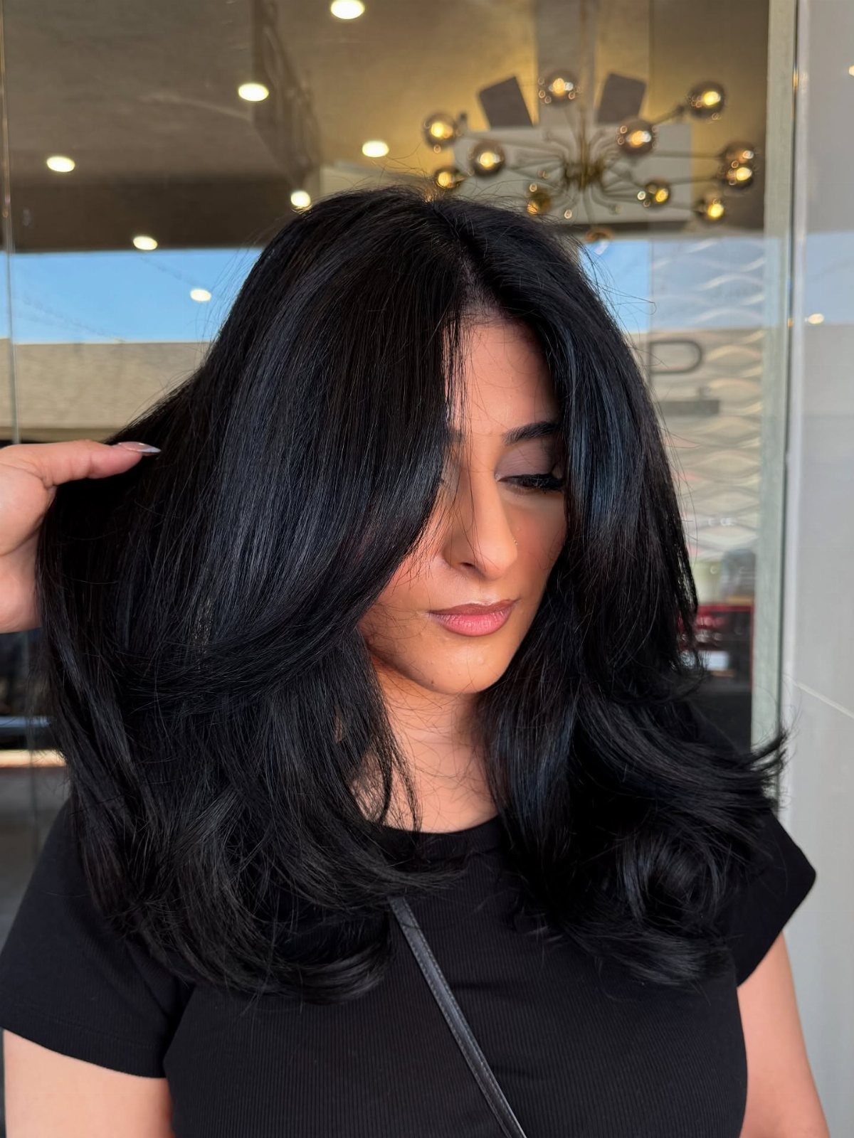 Woman with glossy black layered hair styled in loose waves