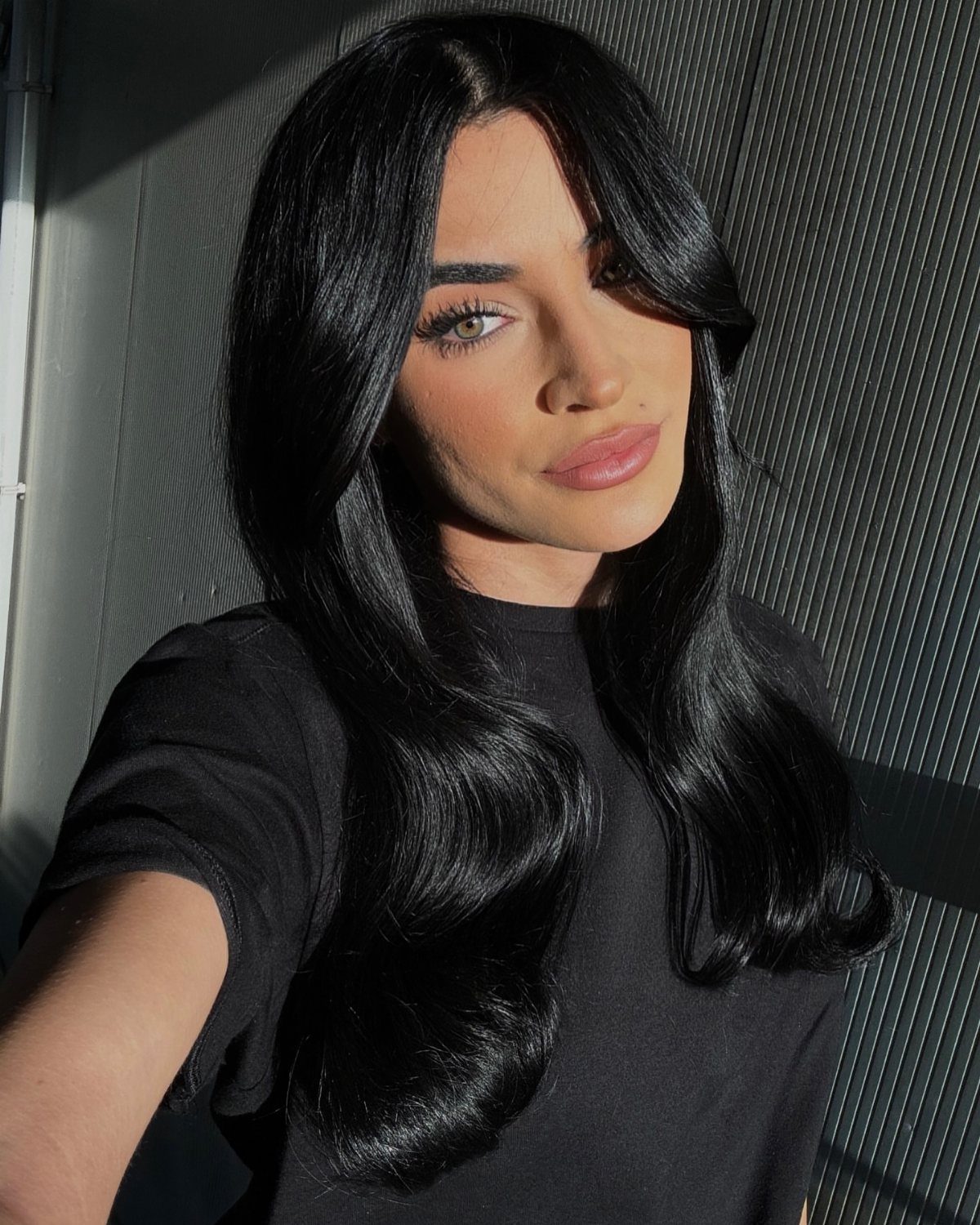 Long black hair falls in glossy, loose waves around a person’s face