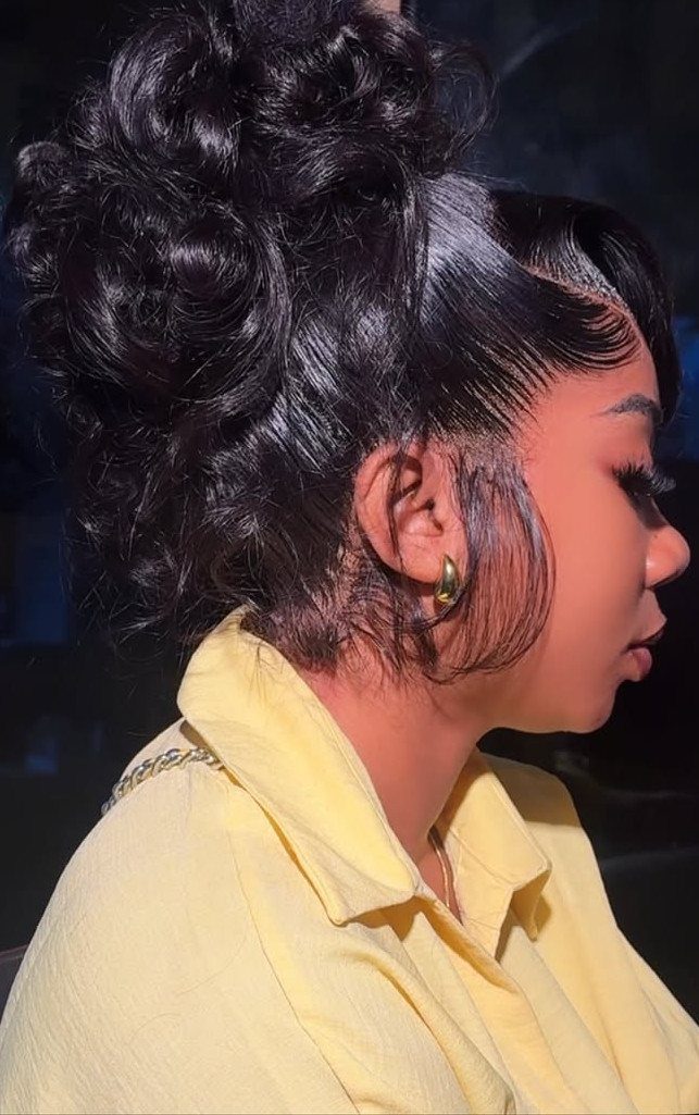 Curly black messy bun with loose face-framing curls and styled edges