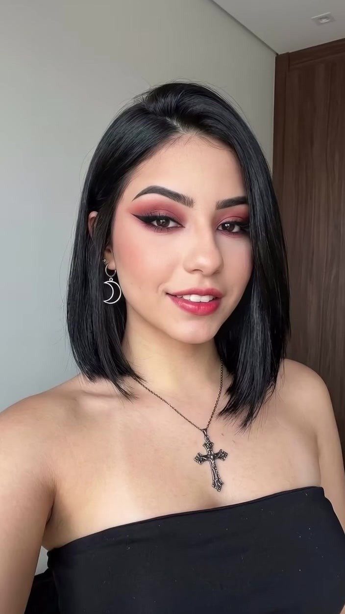 Woman with a smooth jet-black bob and near-middle part poses indoors