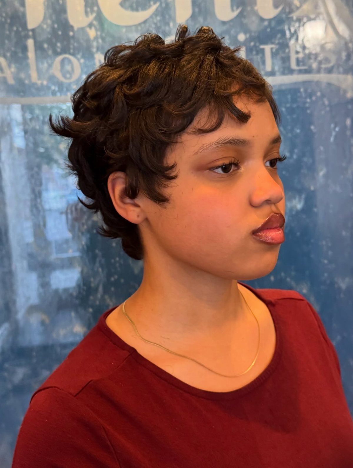 Short layered tapered haircut with tousled curls on a person in profile