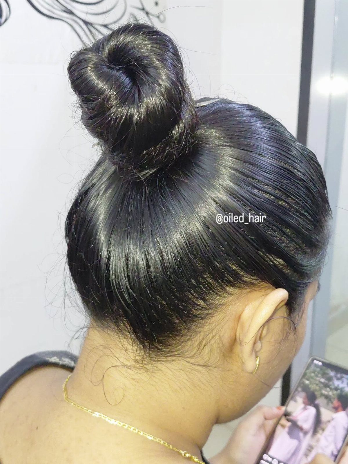 Jet-black hair swept tightly into a glossy top knot bun at the crown