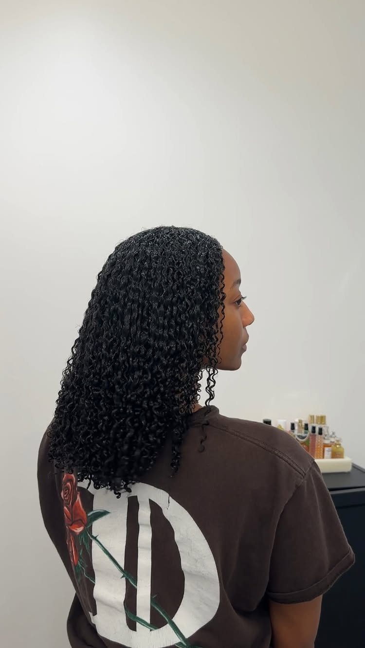 Long natural black curls hang loose down a person's back