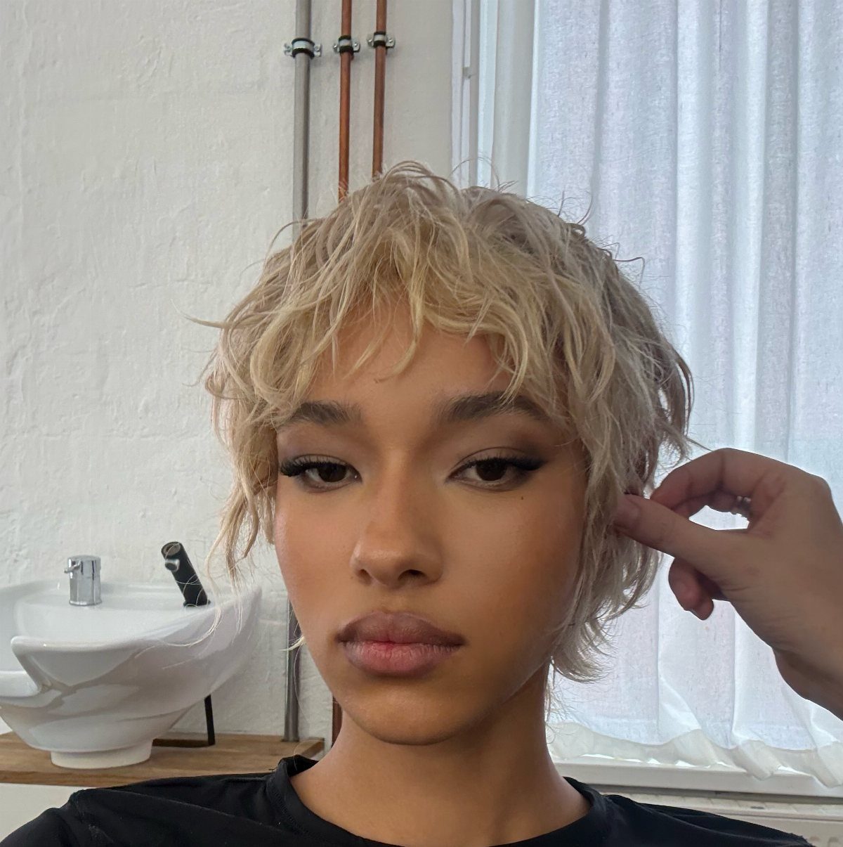 Person with tousled choppy blonde pixie hair in a salon