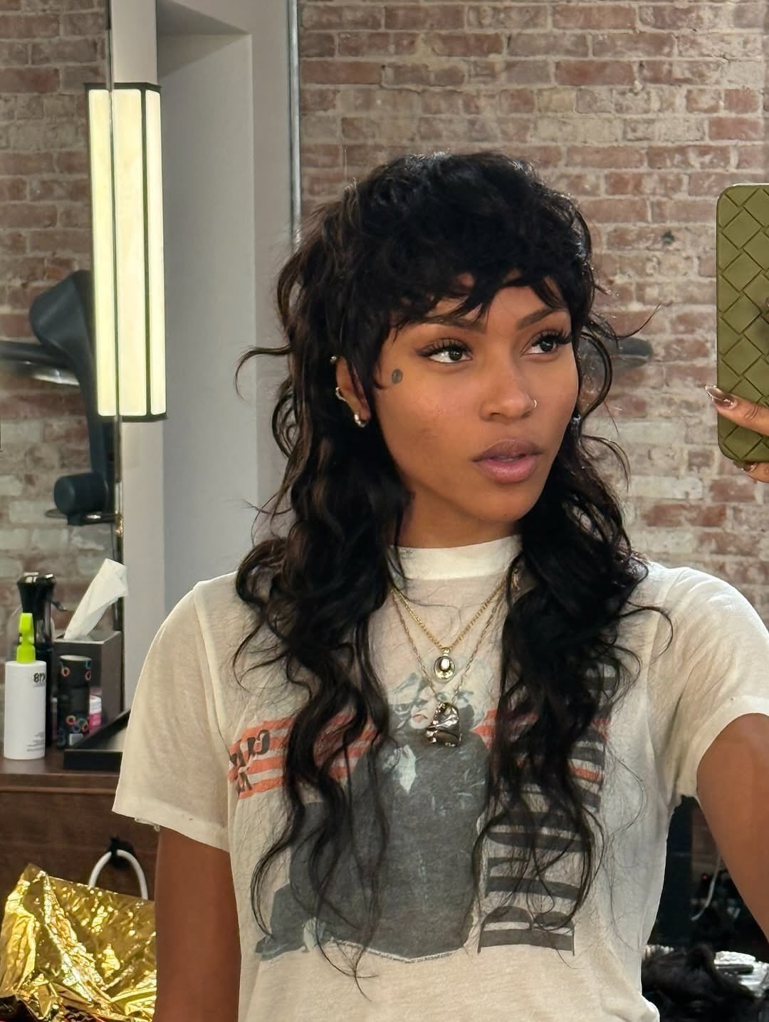 Woman showing a dark curly mullet with short bangs and long, textured lengths