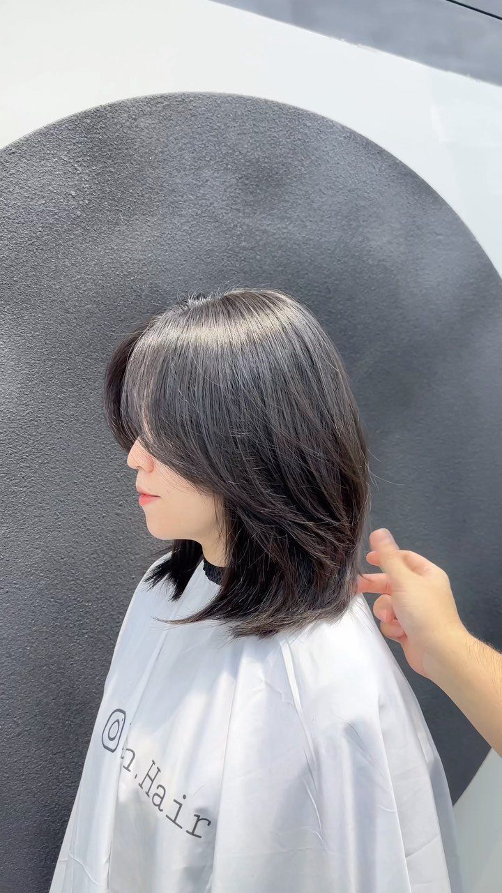 Layered lob with side-swept bangs and feathered ends in a salon